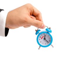 hand holding alarm clock for hours worked
