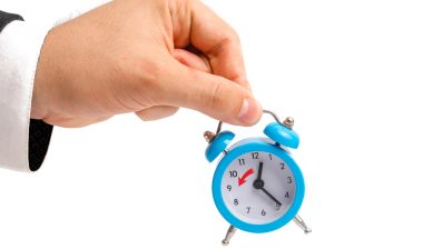 hand holding alarm clock for hours worked