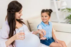 Child handing pregnant mother pills