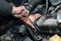 close up of hands working on car engine