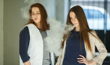 Two girls use e-cigarettes.