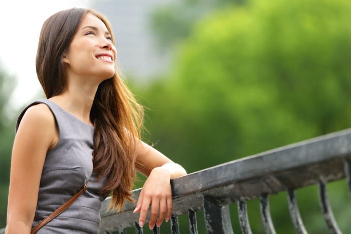 A young woman stands by a railing.