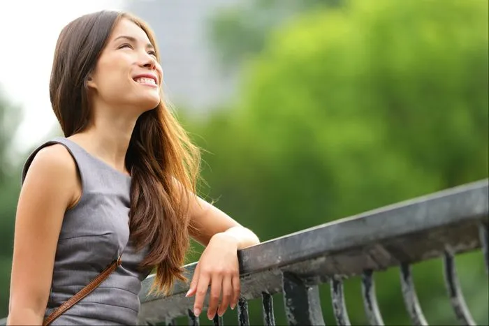 A young woman stands by a railing.