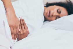 Woman lying on bed with abdominal pain