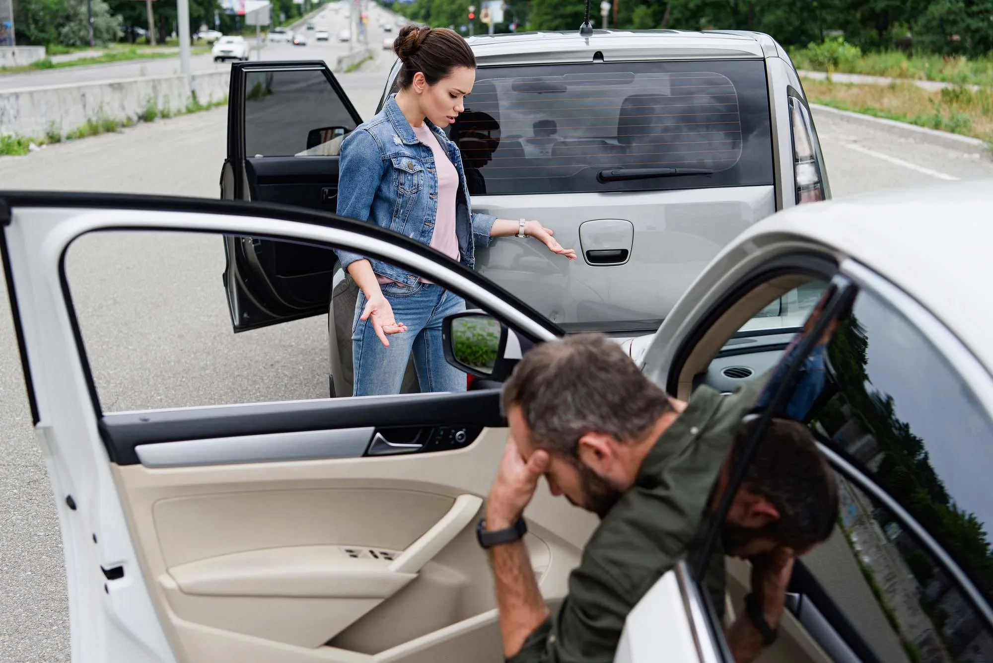 Female driver looking at cars after car accident on road