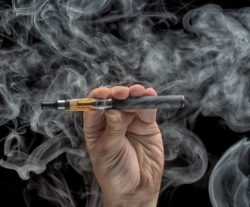 Hand holding an electronic cigarette over a dark background