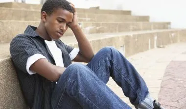 A boy sits by stairs.
