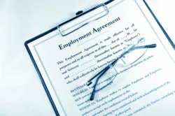 Employment agreement with folded glasses on clipboard