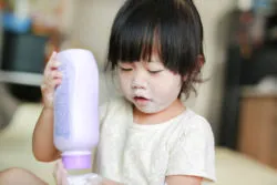 A girl plays with a bottle of talcum powder.