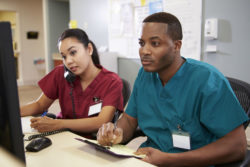 Two nurses work at computers.