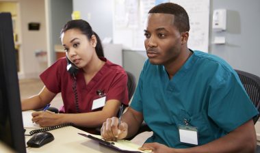 Two nurses work at computers.