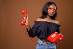 A woman rolls her eyes while holding a phone.