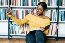 A woman takes a selfie in a bookstore.