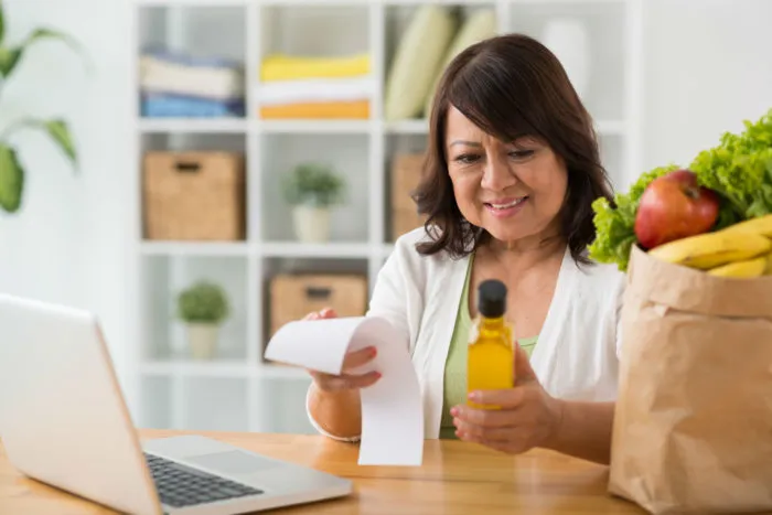A woman reads a grocery receipt.