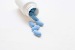 Blue tablets spill out of a bottle.