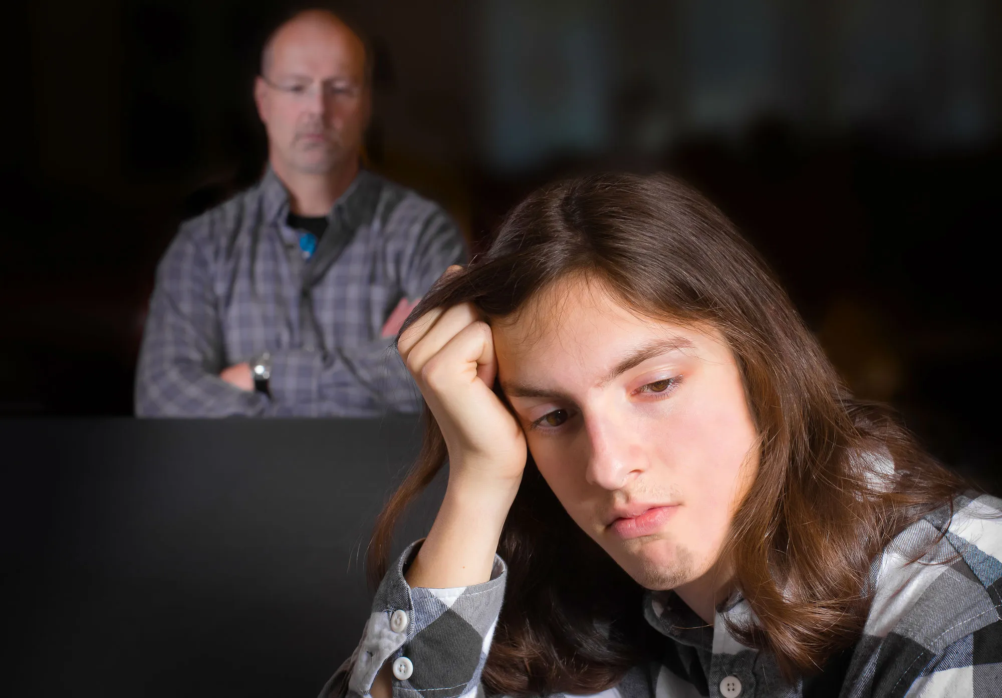 A boy sulks while his dad watches.