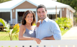 A couple stands in front of a house.