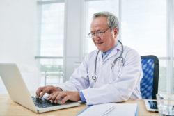 A doctor works at a computer.