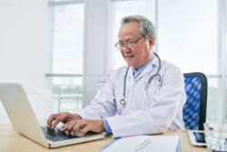 A doctor works at a computer.