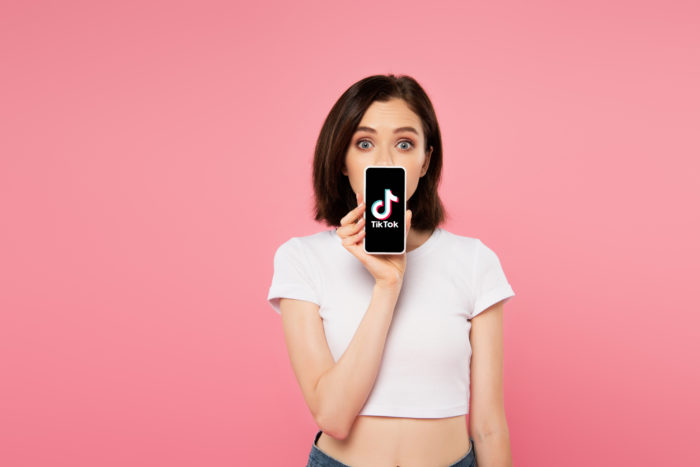 girl holding smartphone with tiktok app open
