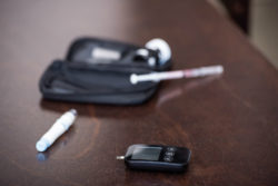 Glucose monitor, diabetes medication, syringe, case on table