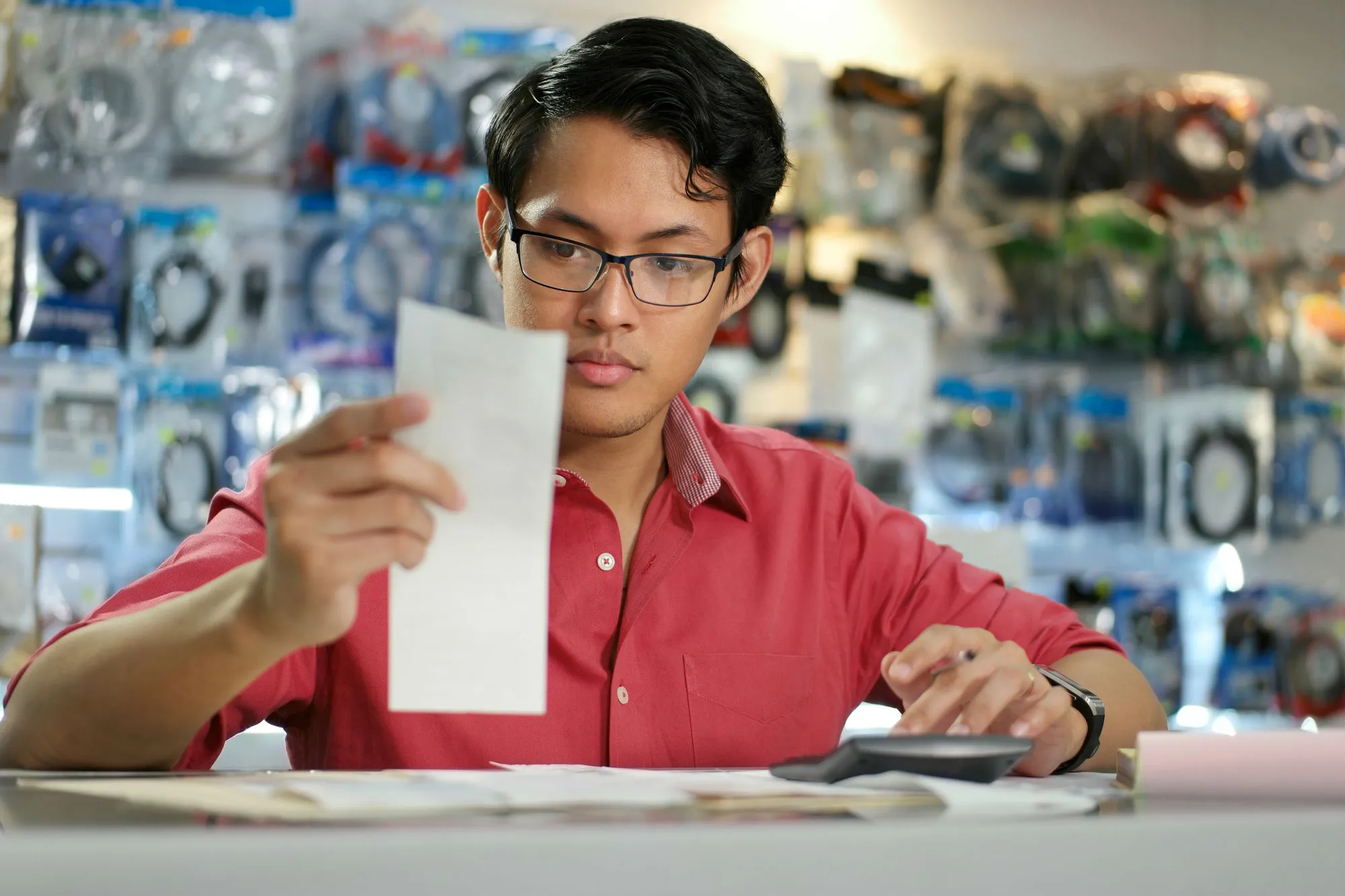 A man in an electronics shop reads a receipt.