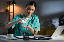 A nurse takes a pill while working at night.