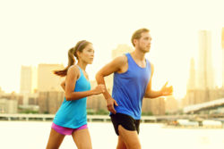A couple runs by a river.
