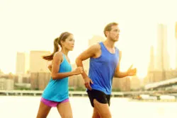 A couple runs by a river.