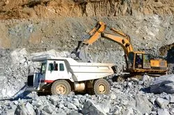 An earth mover loads a dump truck.
