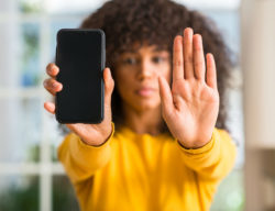Woman holding phone and hand up, stop