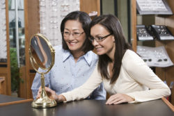 Two women try on glasses.