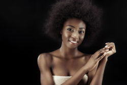 African American woman smiles and is wrapped in a towel.