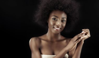 African American woman smiles and is wrapped in a towel.