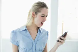 Angry businesswoman reads text on smartphone