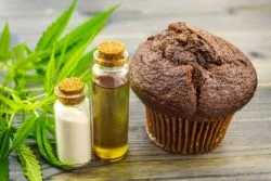 CBD oil, lotion, and edible next to pot leaves