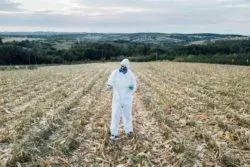 Worker in field using Roundup in Canada