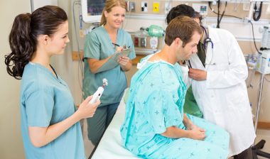 doctor listening to client lungs in hospital
