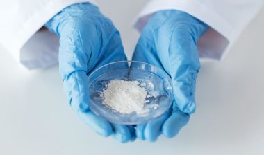 Scientist holding petri dish of white powder