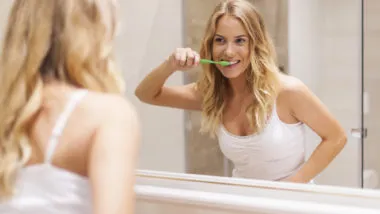 woman brushing teeth with Tom's natural toothpaste