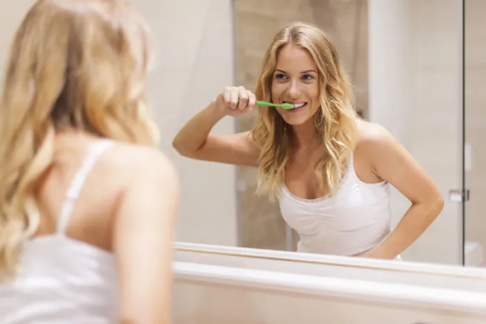 woman brushing teeth with Tom's natural toothpaste