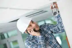Man installing indoor camera at home while on cell phone