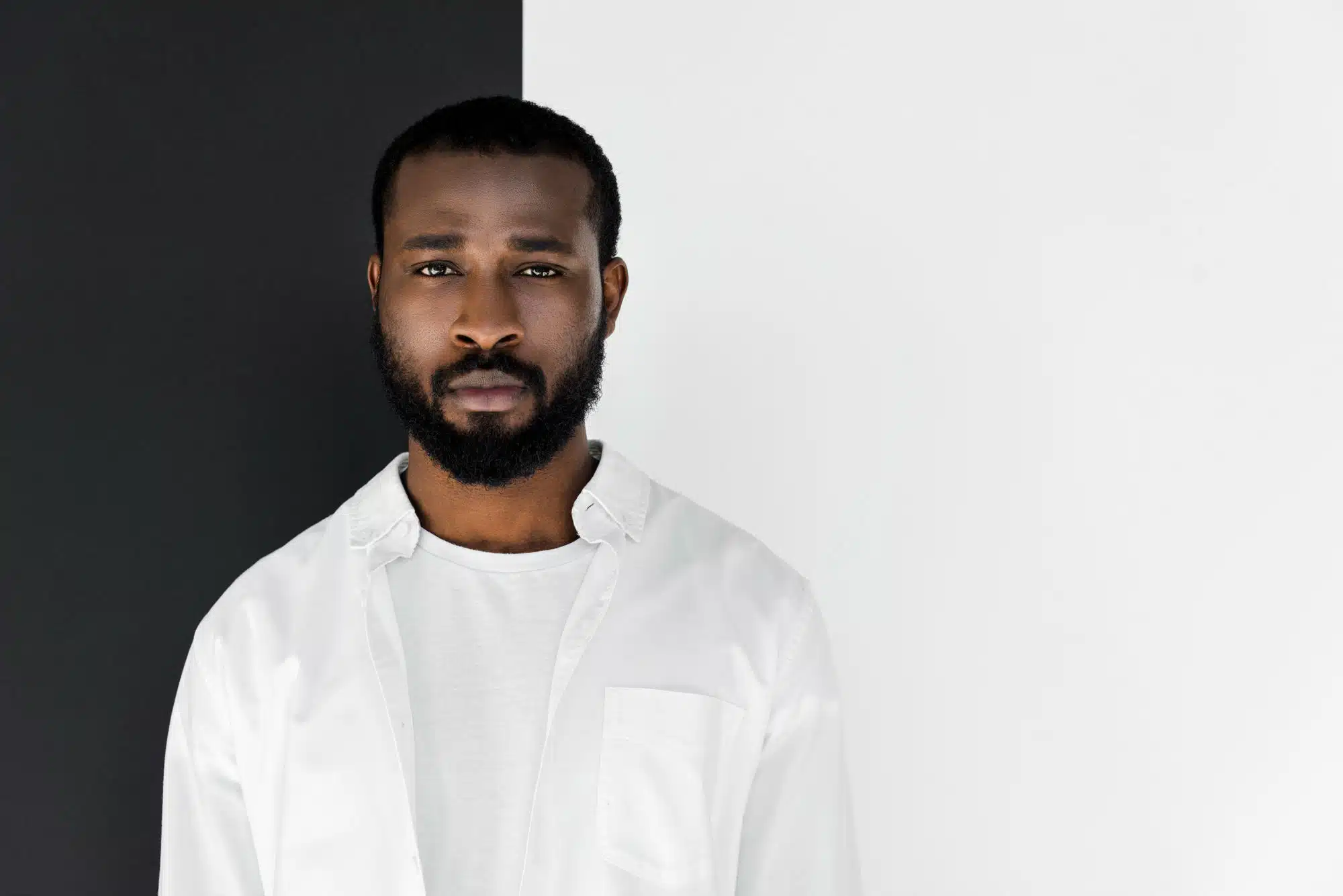 African American man with a serious expression in front of a black and white background.