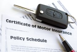Car key on car insurance papers