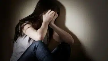 A girl covers her face with her hands.