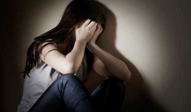 A girl covers her face with her hands.