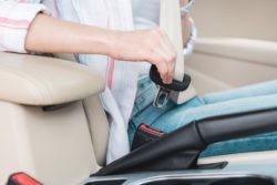woman buckling seat belt in car