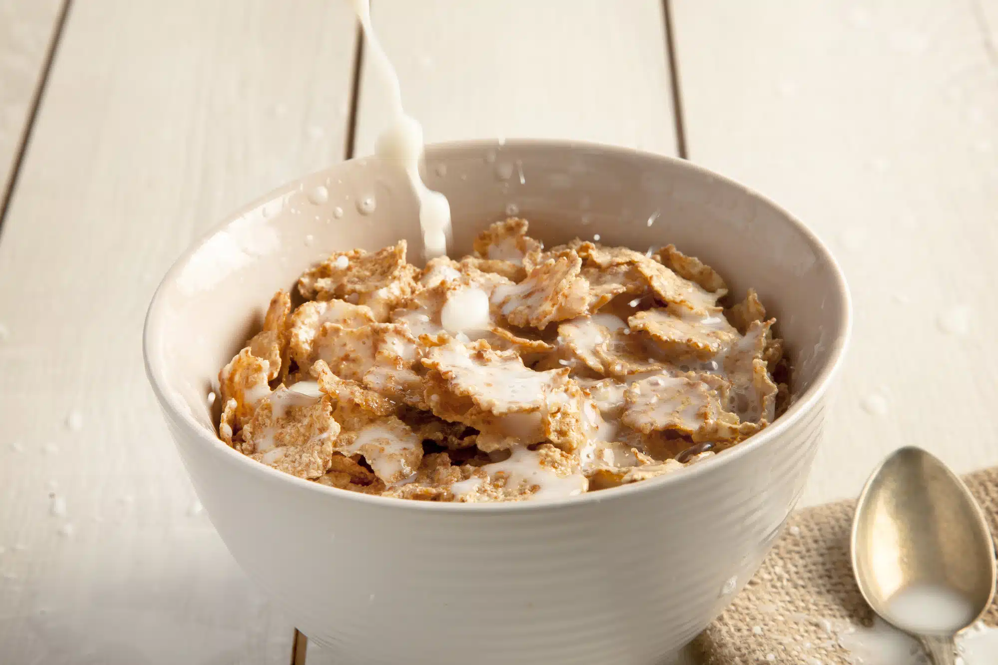 Milk is poured onto a bowl of cereal flakes - post products