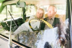 Elderly couple looks through windshield cleaned by windshield wiper.