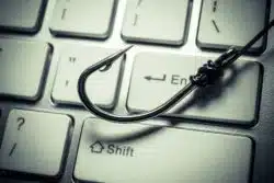 A fishhook lies on a keyboard.